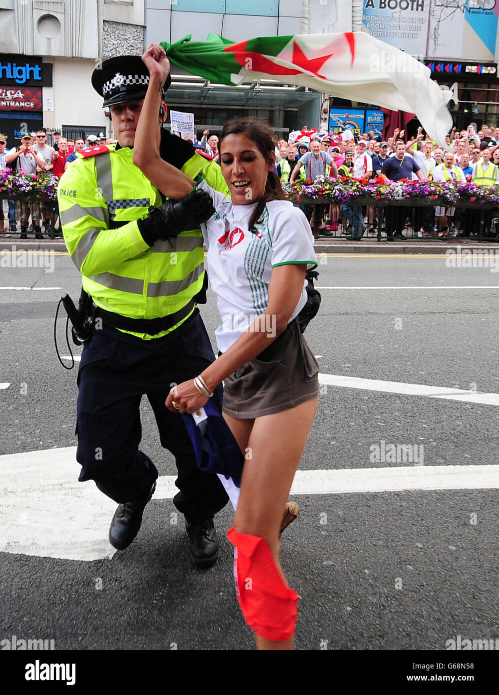 Una donna con bandiera algerina viene rimossa dalla polizia mentre i membri dell'EDL si riuniscono a marzo in Piazza Centenario a Birmingham. Foto Stock