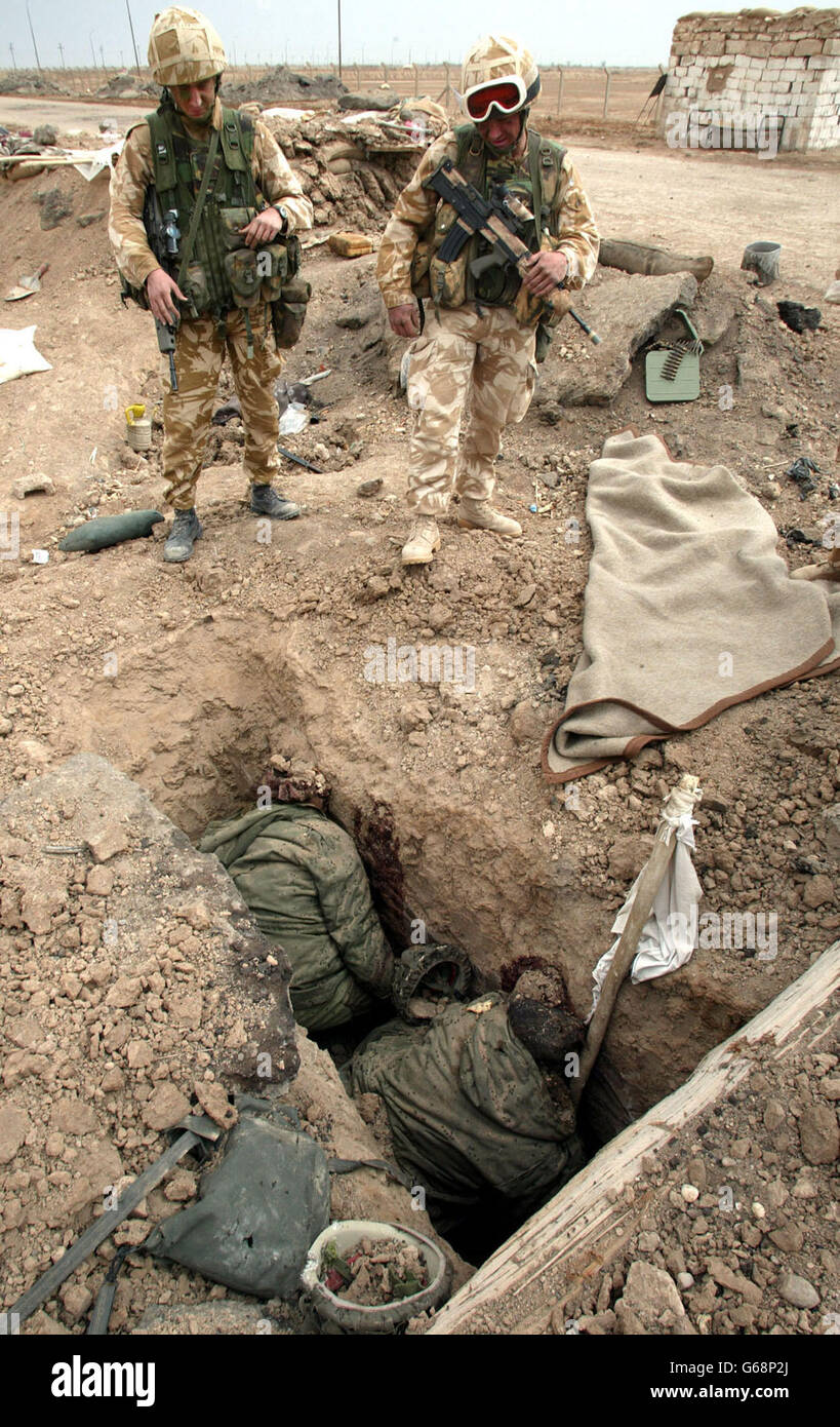 I soldati britannici valutano i danni causati alle posizioni irachene di trincea, mentre i corpi di due soldati iracheni rimangono nella loro trincea con una bandiera bianca, a seguito dell'attacco britannico alla penisola di al-FAW nell'Iraq meridionale. Foto Stock