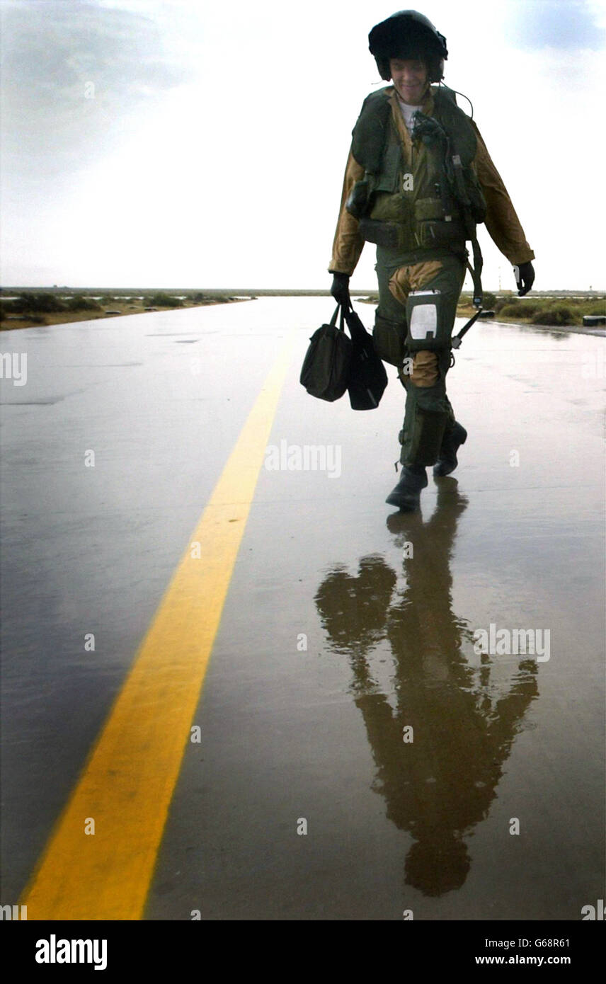 Il pilota britannico della Royal Air Force Harrier GR7 Flt Lt Scott Williams si allontana dal suo Harrier GR7 guidando la pioggia sulla base in Kuwait dopo la sua missione sull'Iraq. Foto Stock