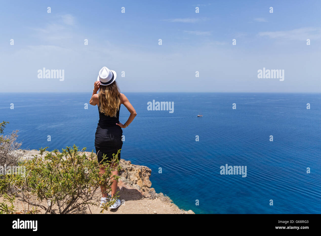 Giovane ragazza in un abito nero guardando il mare Foto Stock