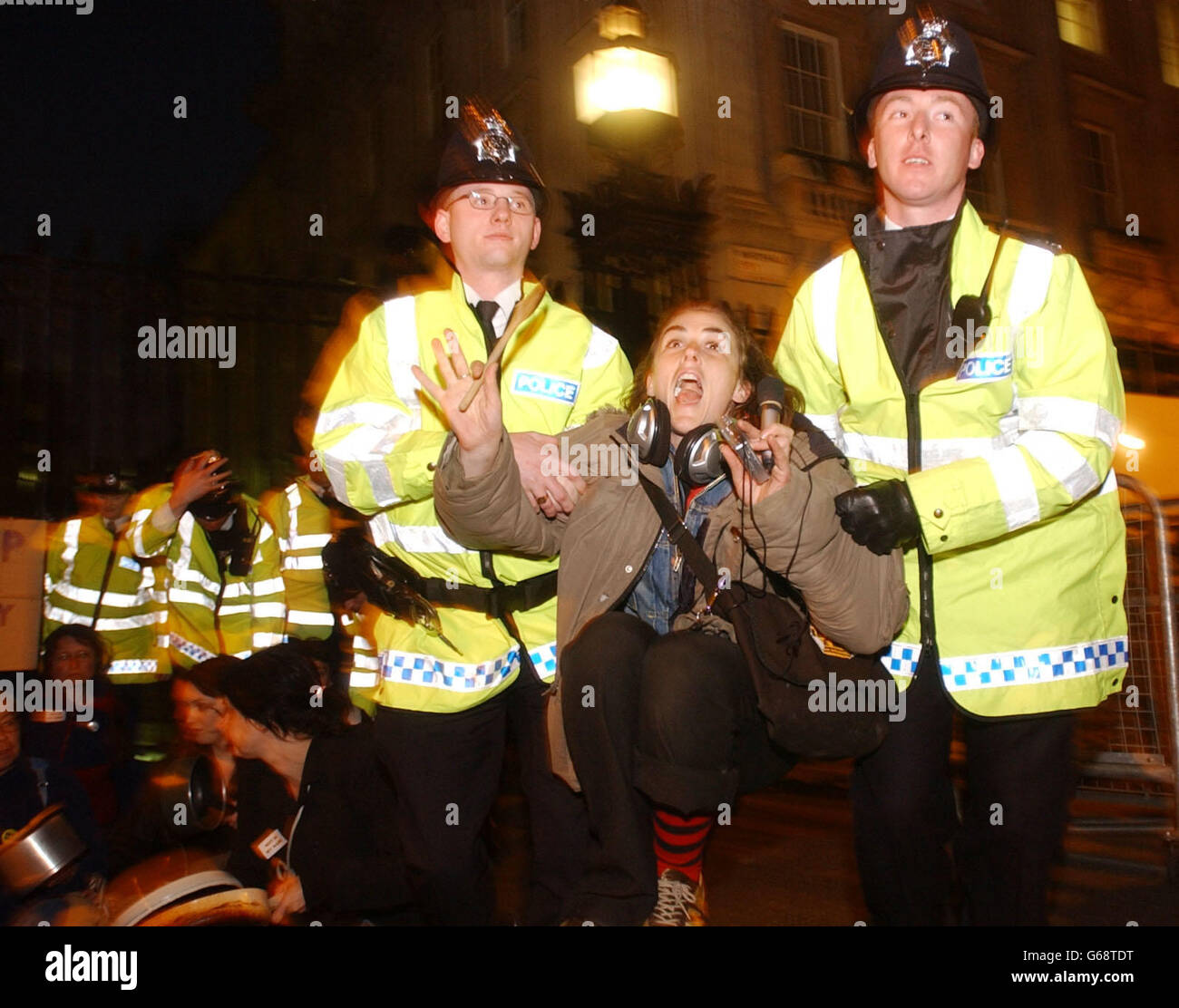 Una donna è guidata via dalla polizia durante una protesta contro la guerra in Iraq che ha coinvolto banging pentole fuori dalle porte di Downing Street nel centro di Londra. Foto Stock