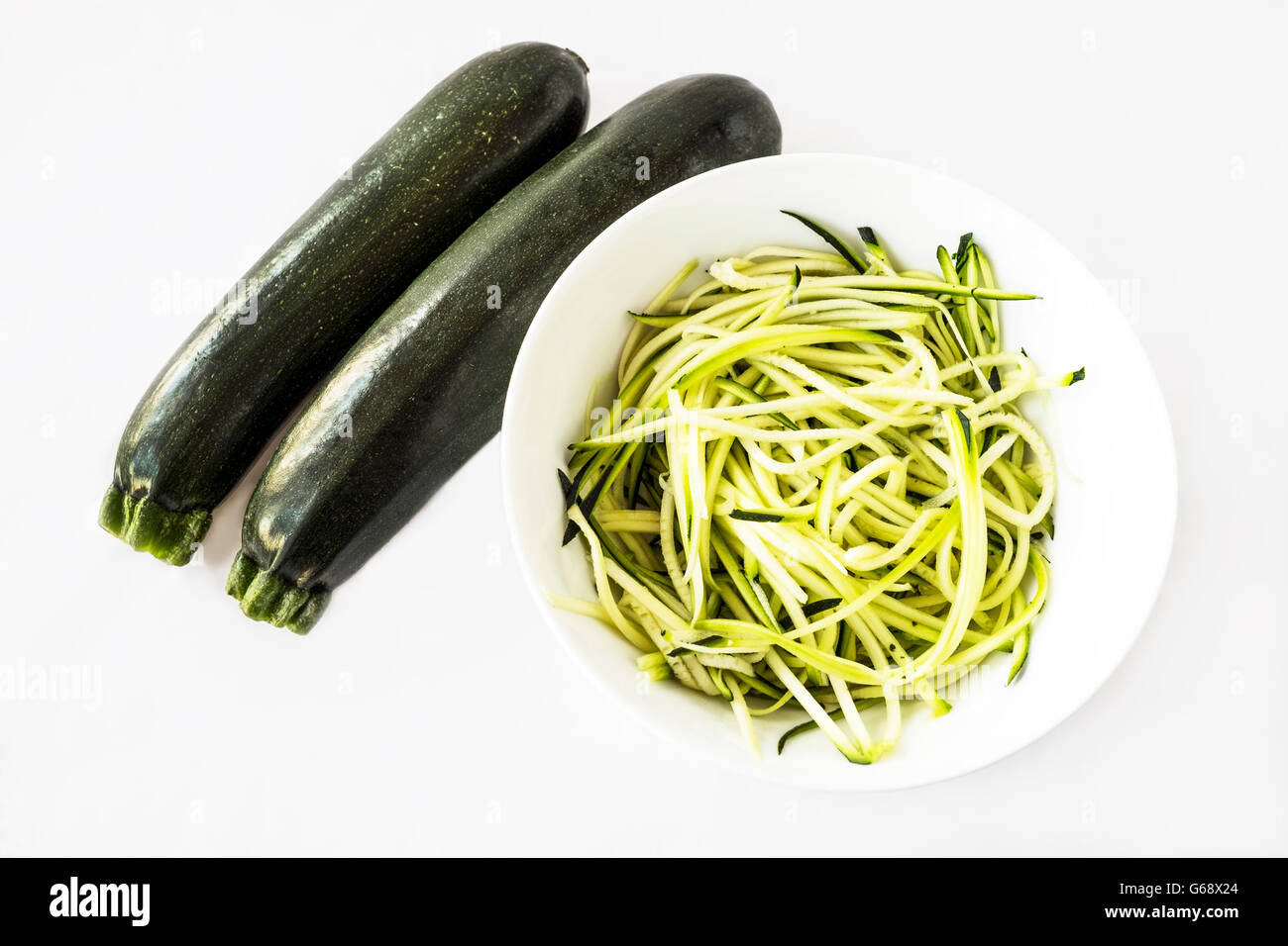 Due o di zucchine zucchine con alcuni spiralizzato per sostituire la pasta in una ciotola bianco su sfondo bianco Foto Stock