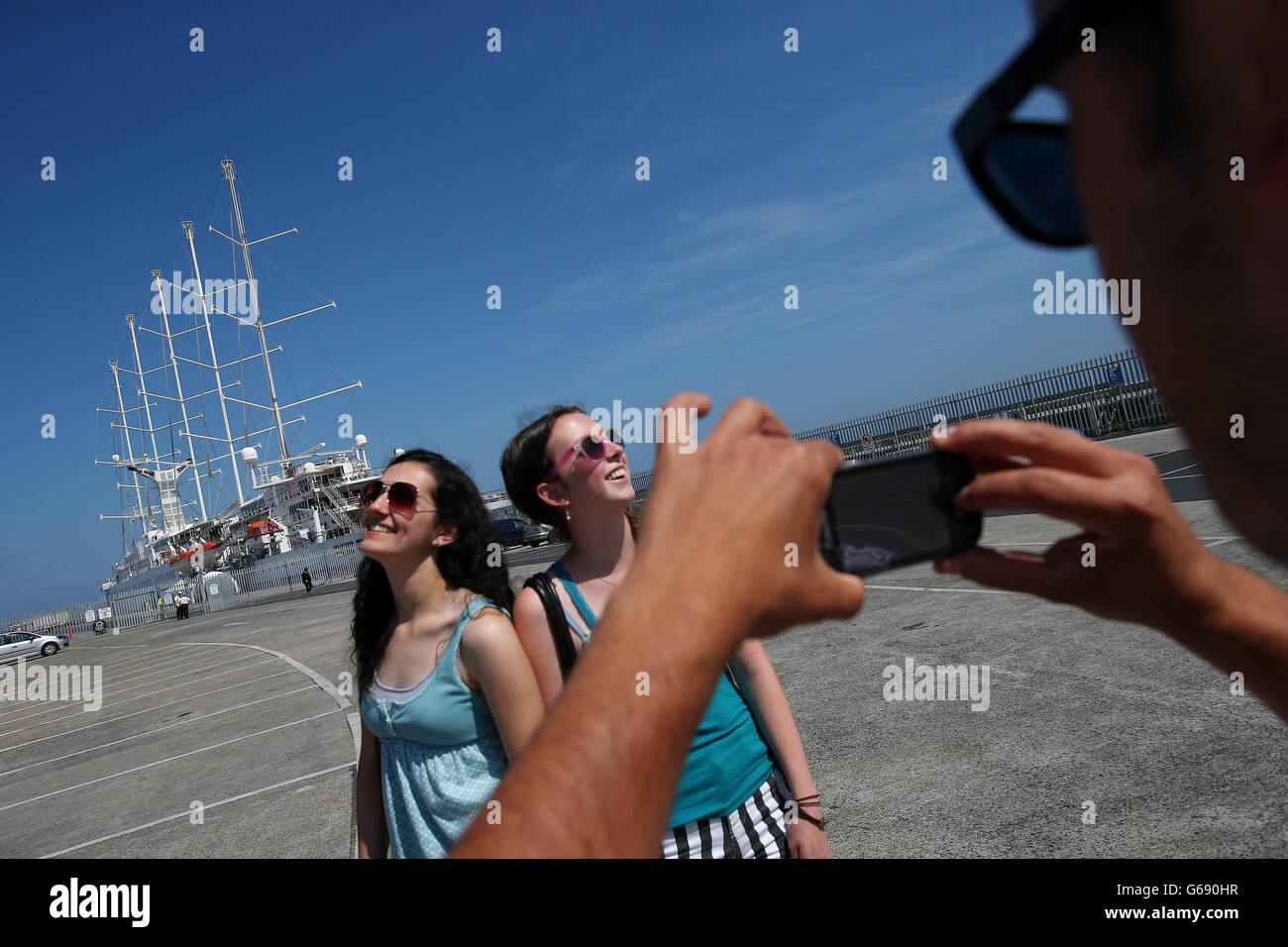 Due donne hanno la loro foto scattata di fronte al Wind Surf, Dun Laoghaire Harbour, Dublino. Foto Stock