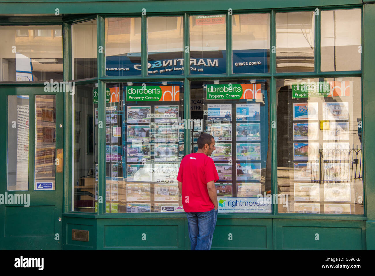 Un uomo in cerca di un agenti immobiliari vetrina Foto Stock