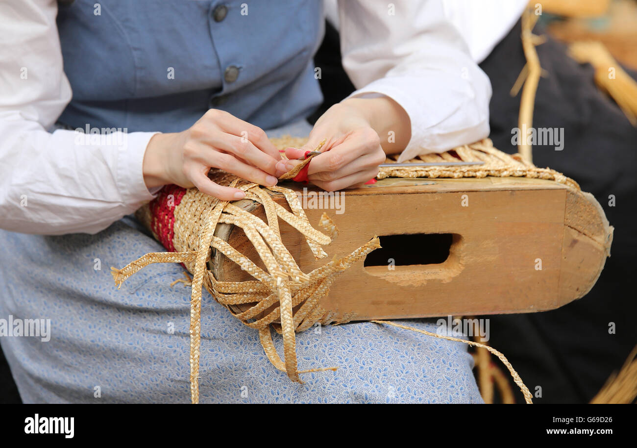 Ragazza giovane con dita affusolate della mano crea pazientemente un sacco di paglia Foto Stock