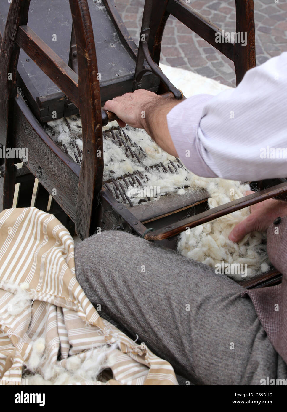 Carda mentre la cardatura lana o cotone con la vecchia macchina in legno Foto Stock
