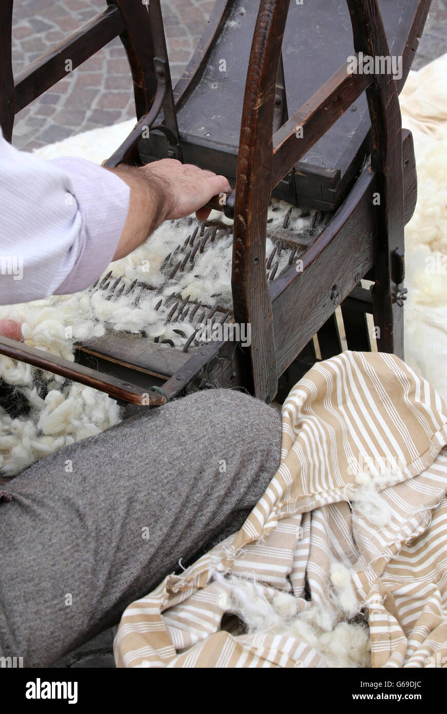 Il sambuco carda mentre la cardatura lana o cotone con la vecchia macchina di legno per fare i cuscini e materassi Foto Stock