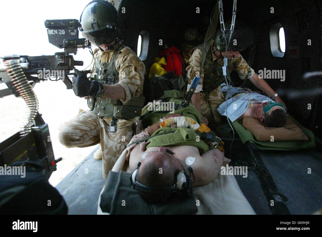 Il Crewman RAF (a sinistra) tiene la guardia con una mitragliatrice GPMG dall'elicottero Puma, mentre il medico RAF tende a rapinare ferite su due marines britannici dal comando 42, Iraq. Foto Stock