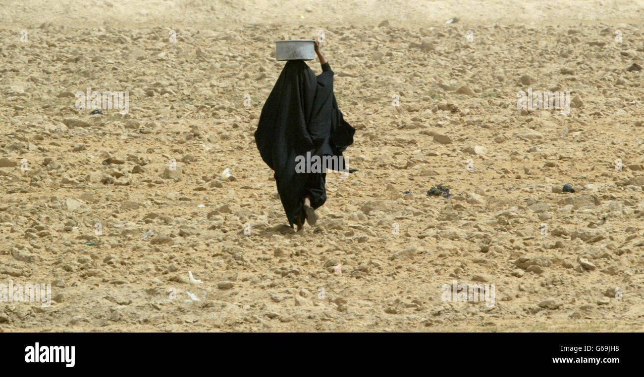 Una donna si allontana con un contenitore d'acqua bilanciato sulla sua testa che è stato consegnato dal britannico 23 Pioneer Regiment da una petroliera nella città meridionale irachena di Safwan. Le forze britanniche stanno aiutando la popolazione locale con aiuti umanitari. Foto Stock