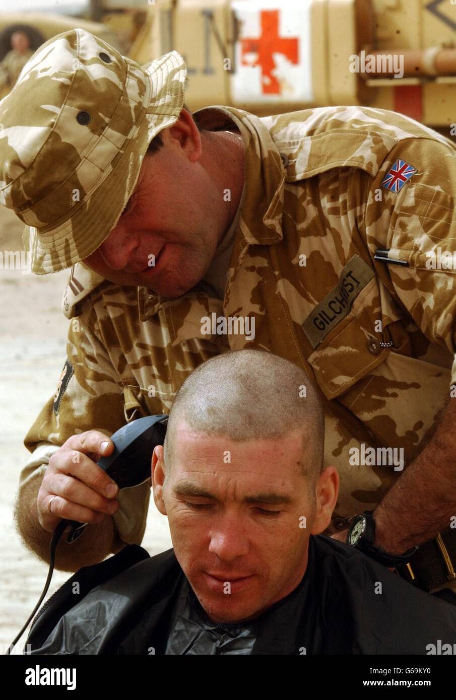 I membri della Guardia Irlandese CPL Gilchrist danno all'unità Padre, Ian Stevenson, una breve schiena e lati a Basra. Foto Stock