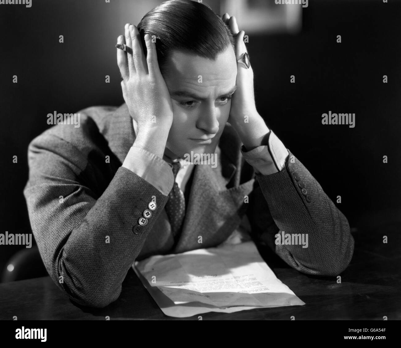 1930s premuto il business man tenendo la testa con le mani sopra i suoi orecchi Foto Stock