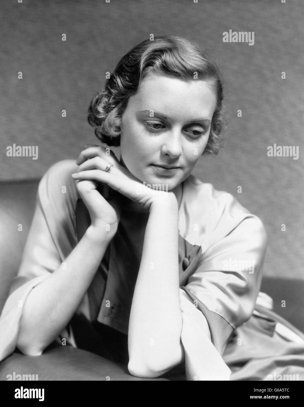 1930s ritratto pensieroso donna seduta nella sedia mento pendente sul pensiero a mano Foto Stock