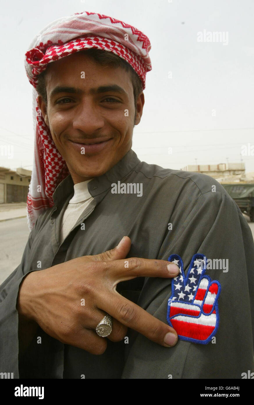 Un ragazzo mostra con orgoglio il suo distintivo con la bandiera degli Stati Uniti su di esso come la pattuglia reggimento dell'aeronautica reale britannica nella città irachena meridionale di Safwan. Le forze britanniche stanno aiutando la popolazione locale con aiuti umanitari. Foto Stock