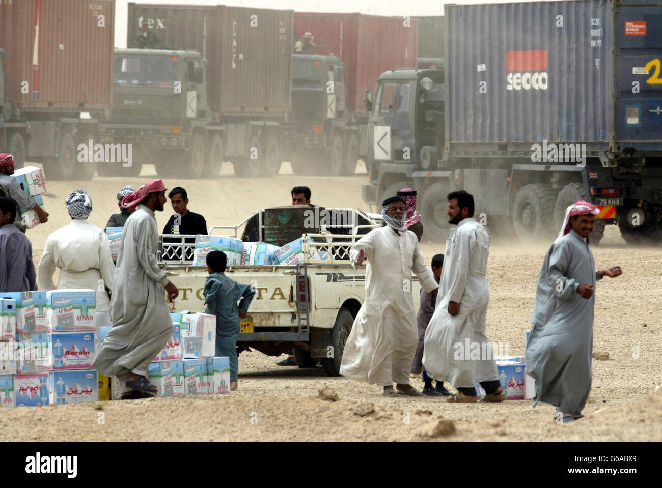 Gli abitanti del villaggio raccolgono le forniture come membri del 3 Regt Army Air Corp CIMIC (civile squadra di cooperazione militare) distribuire carburante e acqua ai villaggi degli arabi paludi nel sud dell'Iraq, come parte dell'operazione irachena libertà. Foto Stock