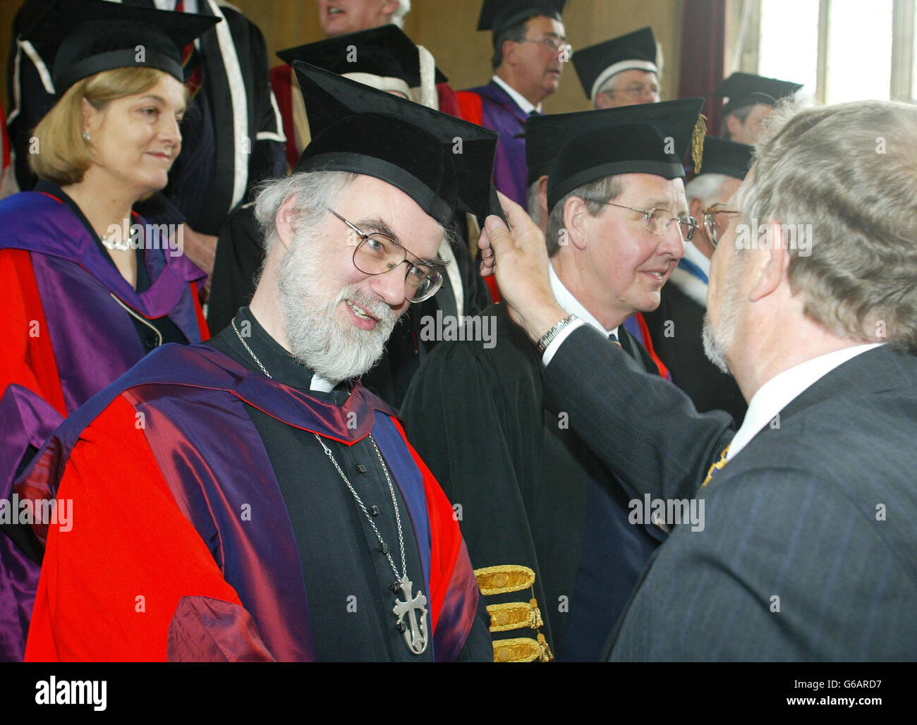 Un funzionario adegua il cappello del Reverendo e dell'onorevole Rowan  Williams, l'Arcivescovo di Canterbury, dopo aver conseguito la laurea  onoraria presso la Bangor University nel Galles del Nord Foto stock - Alamy
