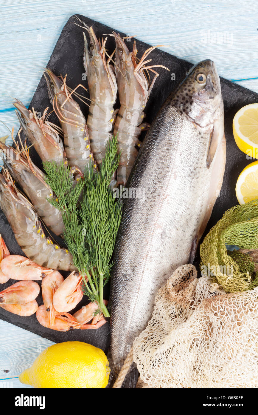 Crudo fresco il cibo del mare con spezie sulla lastra di pietra su un tavolo di legno dello sfondo. Vista superiore Foto Stock