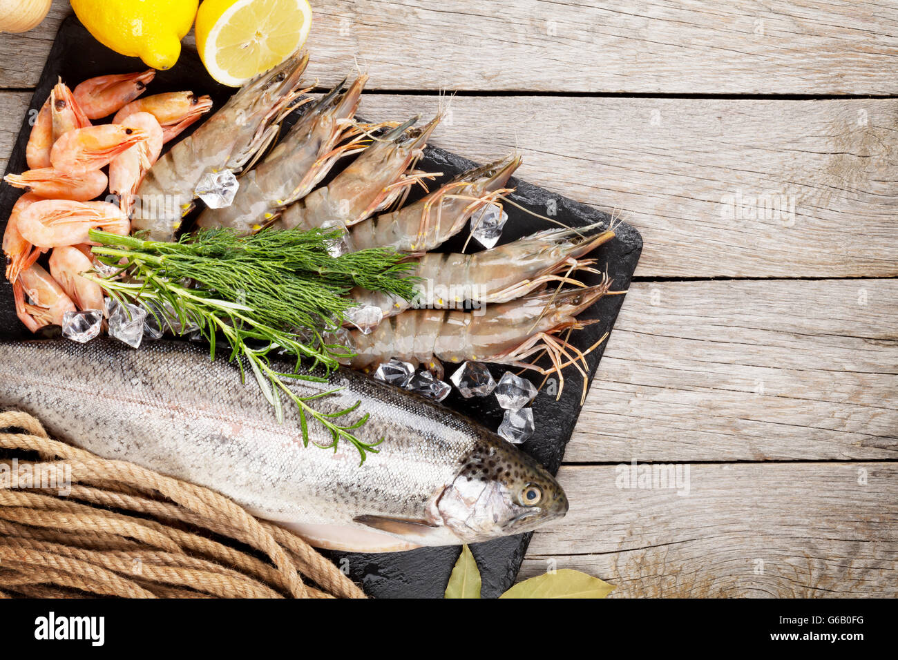 Crudo fresco il cibo del mare con spezie sulla lastra di pietra su un tavolo di legno dello sfondo. Vista superiore Foto Stock