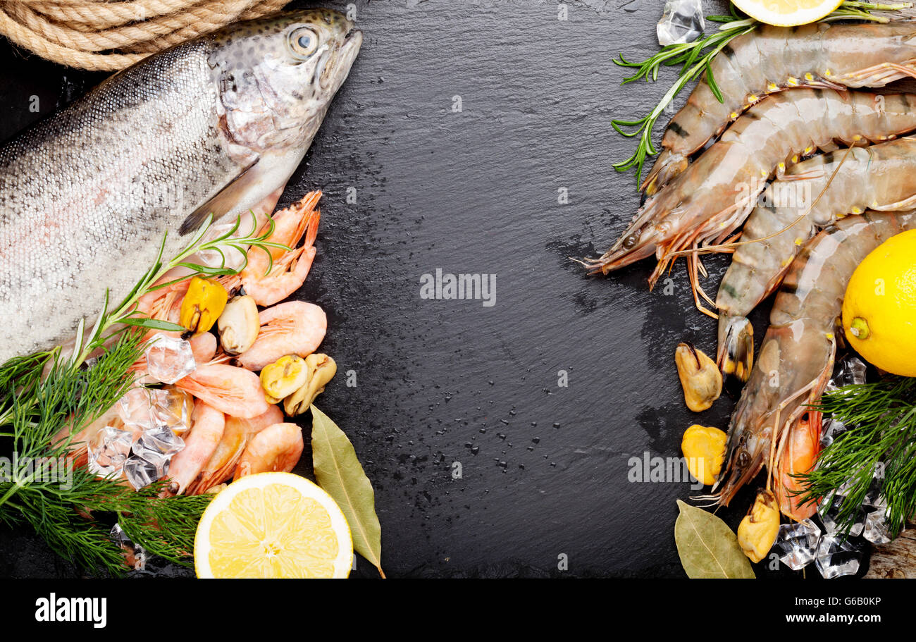 Crudo fresco il cibo del mare con spezie sulla pietra nera dello sfondo. Vista da sopra con lo spazio di copia Foto Stock