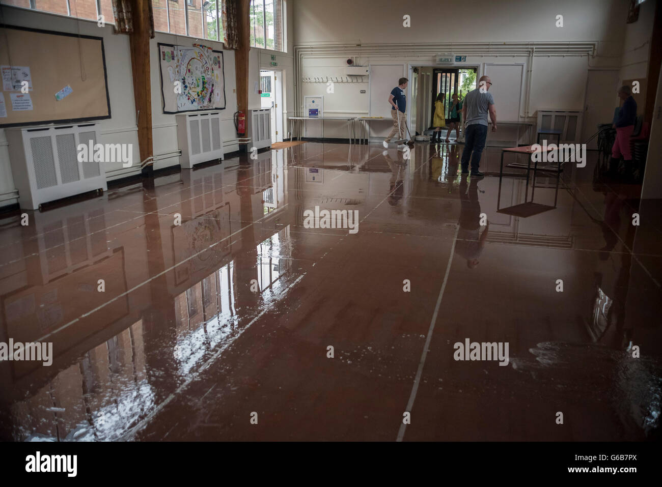 Londra, Regno Unito. Il 23 giugno, 2016. I membri della congregazione utilizzare scope per spazzare via le alluvioni in Emmanuel Church hall dopo una doccia torrenziale, duratura per più di trenta minuti, provoca inondazioni localizzate in Northwood, a nord ovest di Londra. Credito: Stephen Chung / Alamy Live News Foto Stock