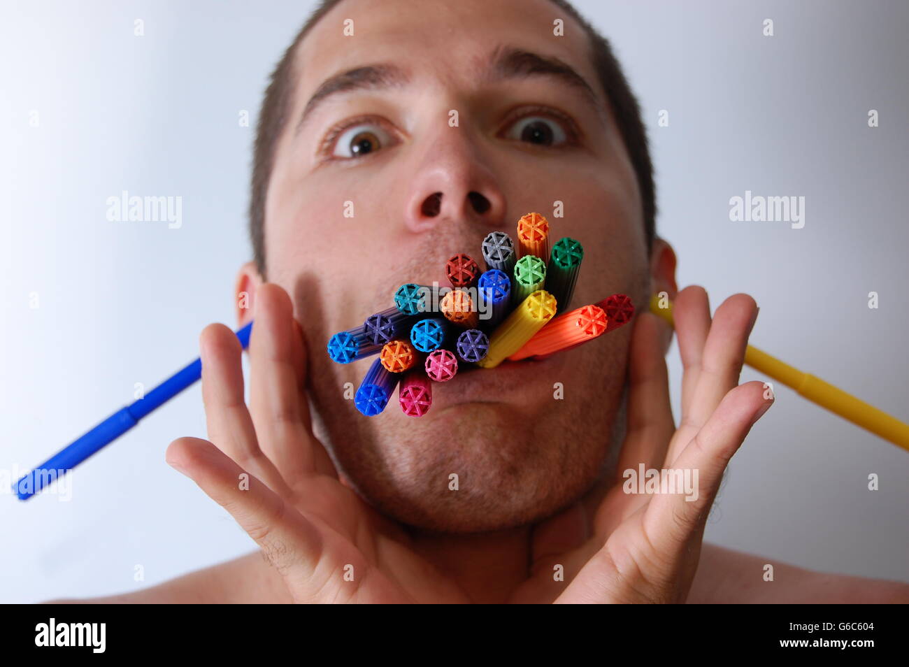 Un uomo mangiare penne colorate Foto Stock