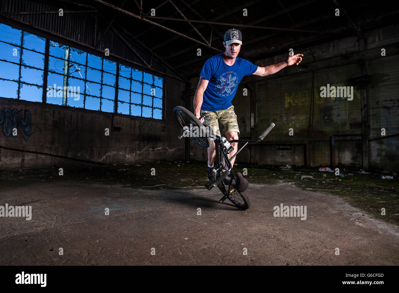 Chris Letchford riding BMX flatland in un vecchio magazzino nella factory di Devonport, la Tasmania. Foto Stock