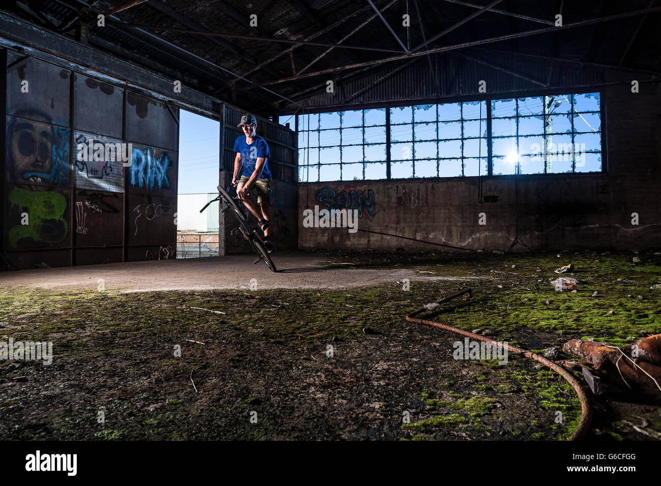 Chris Letchford riding BMX flatland in un vecchio magazzino nella factory di Devonport, la Tasmania. Foto Stock