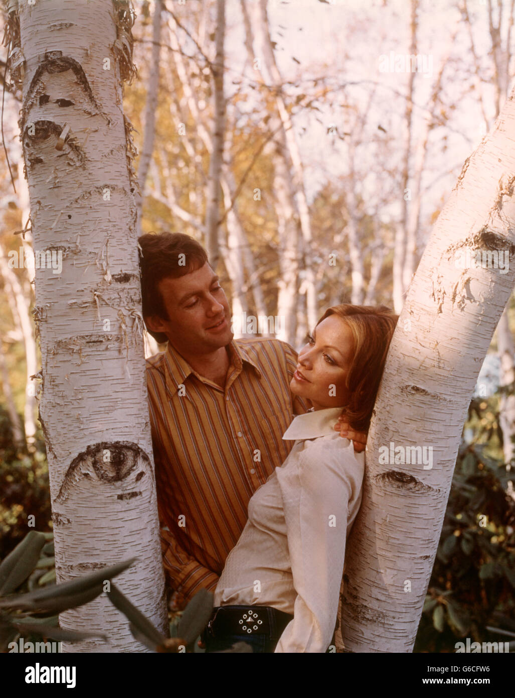 Anni Settanta coppia romantica poggiando su Birch tronco di albero autunno Foto Stock