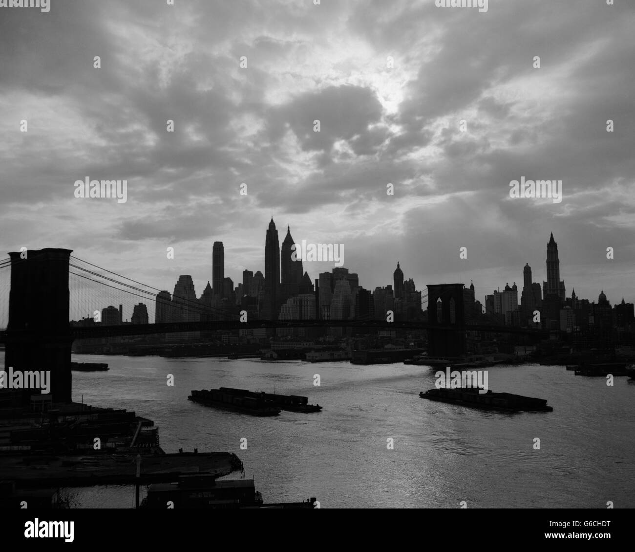Negli anni quaranta anni cinquanta tramonto spettacolare DOWNTOWN NEW YORK skyline della città con il ponte di Brooklyn chiatte in East River New York NY USA Foto Stock