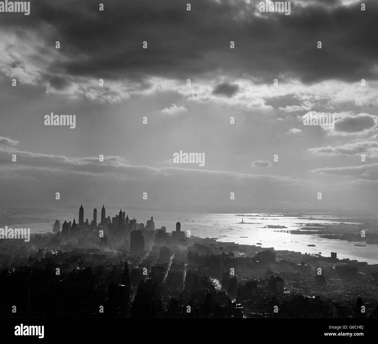 Anni Cinquanta nel tardo pomeriggio getta luce il centro di Manhattan in silhouette SUN riflettendo sulla baia e sul fiume Hudson Foto Stock