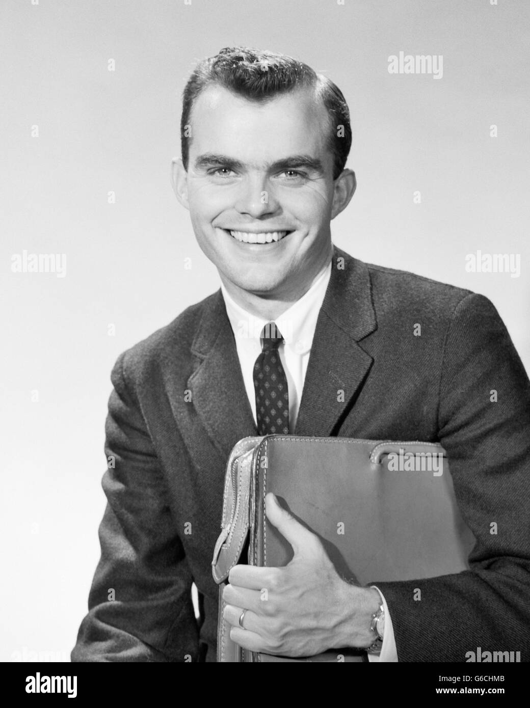 Anni Cinquanta anni sessanta ritratto imprenditore sorridente venditore guardando la telecamera stringendo la sua valigetta Foto Stock