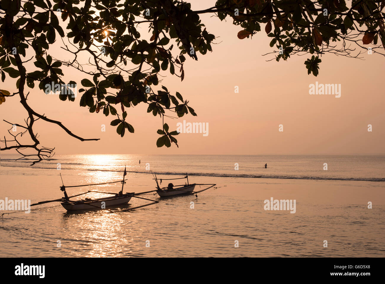 Tranquillo paesaggio del litorale con barche di pescatori sulla calma acqua oceanica e foglie silhouette, soleggiata giornata estiva. Foto Stock