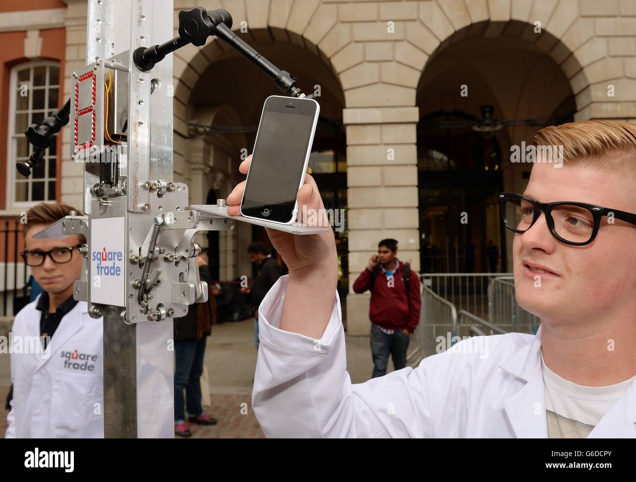 Un lavoratore per Square Trade, una società di garanzie per i telefoni cellulari, inserisce un nuovo iPhone Apple nel "Phone Terminator", per testare le due nuove offerte di Apple fuori dal negozio Apple a Covent Garden a Londra. Dopo averli caditi due volte, entrambi i nuovi modelli sono rimasti graffiati, leggermente danneggiati ma ancora funzionanti. Foto Stock