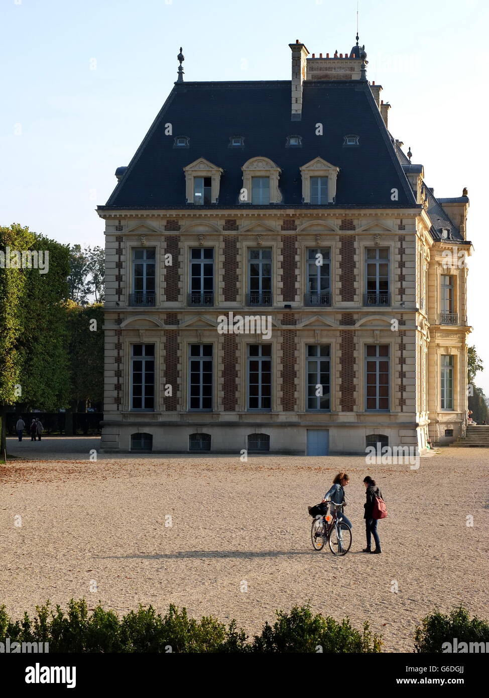 Due giovani donne di parlare gli uni con gli altri con il Chateau de Sceaux in background. Foto Stock