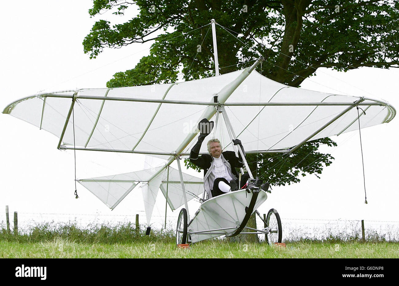 Sir Richard Branson in una replica del velivolo monoplano di Cayley nel 150° anniversario della prima lotta con equipaggio al mondo, a Brompton Dale, vicino Scarborough. Foto Stock