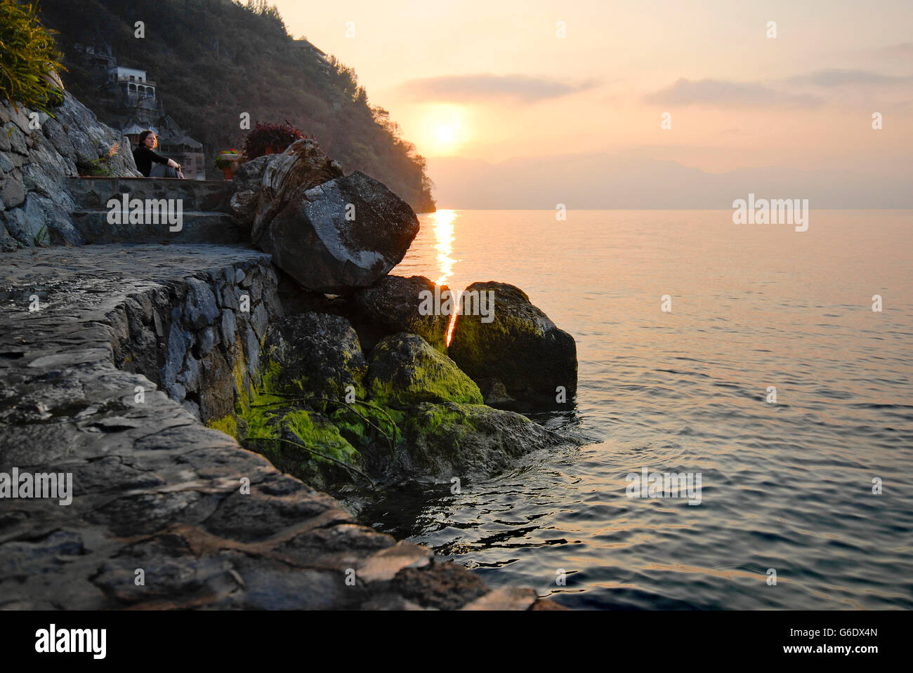 Percorso di pietra sulla riva del lago AtitlÃ¡n, Guatemala, con una donna guarda il sunrise Foto Stock