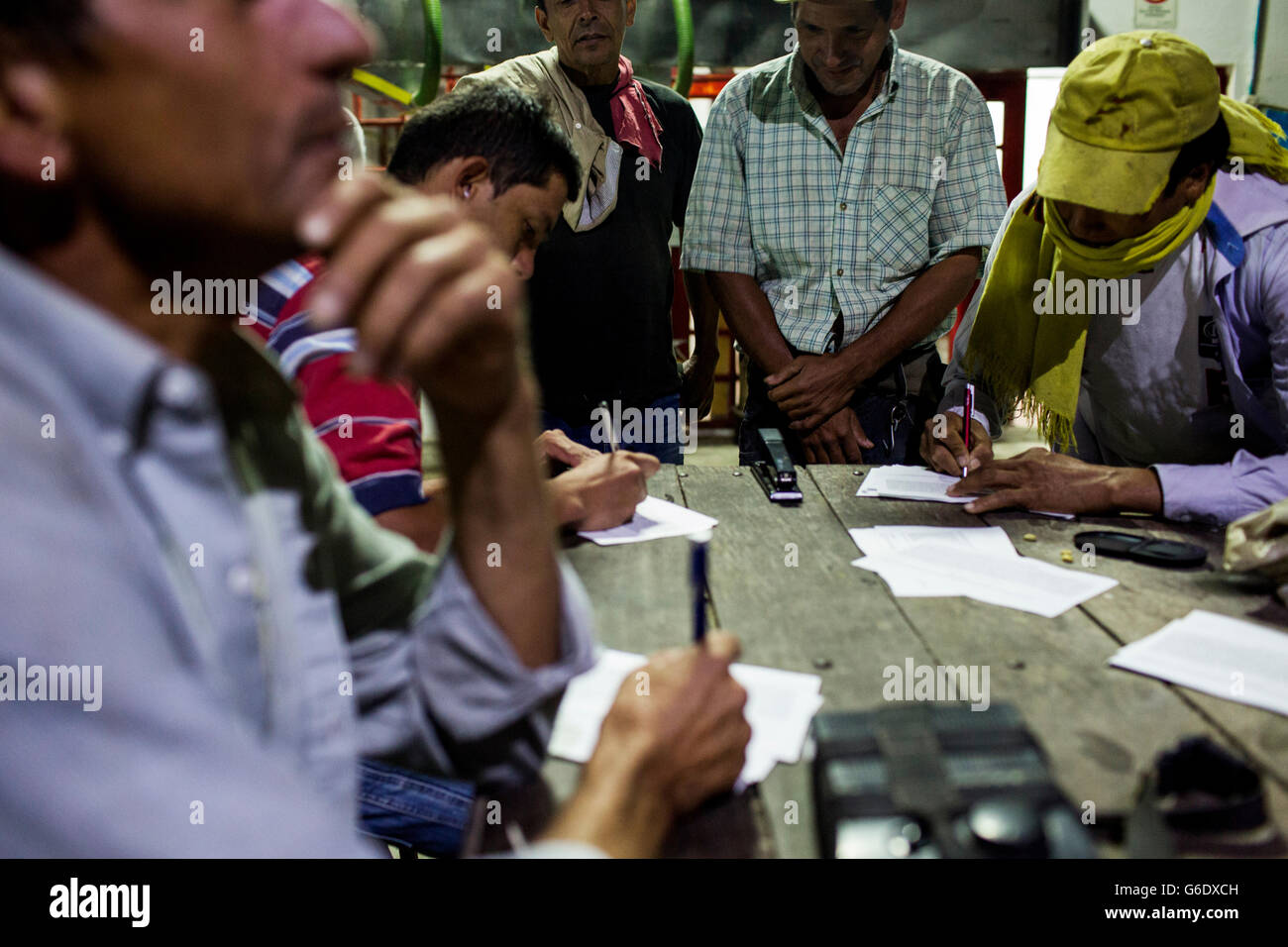 Un gruppo di uomini di compilare rapporti di lavoro dopo un giorno di raccolta delle ciliegie di caffè in Colombia rurale. Foto Stock