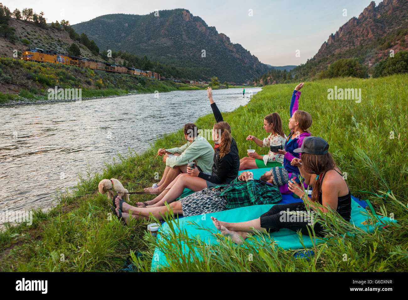 I barcaioli onda al passaggio di un treno merci mentre mangia la cena dalla parte superiore del Fiume Colorado presso i banchi campeggio vicino Kremmling, Colorado. Foto Stock
