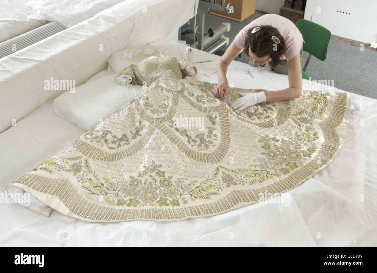 Il Queen's Coronation vestito di raso bianco è preparato, per l'apertura estiva delle sale di Stato di Buckingham Palace da Janet Woods, conservatore di tessuti senior, al lavoro nel Textile Conservation Studio di Hampton Court Palace a SW London. * quando l'abito, disegnato da Norman Hartnell e decorato con ricami in filo d'oro e d'argento, e incrostato con perle di semi e cristalli, è in mostra, i visitatori potranno anche vedere la prima mostra pubblica dell'intero fregio di coronazione di Feliks Topolski. Foto Stock