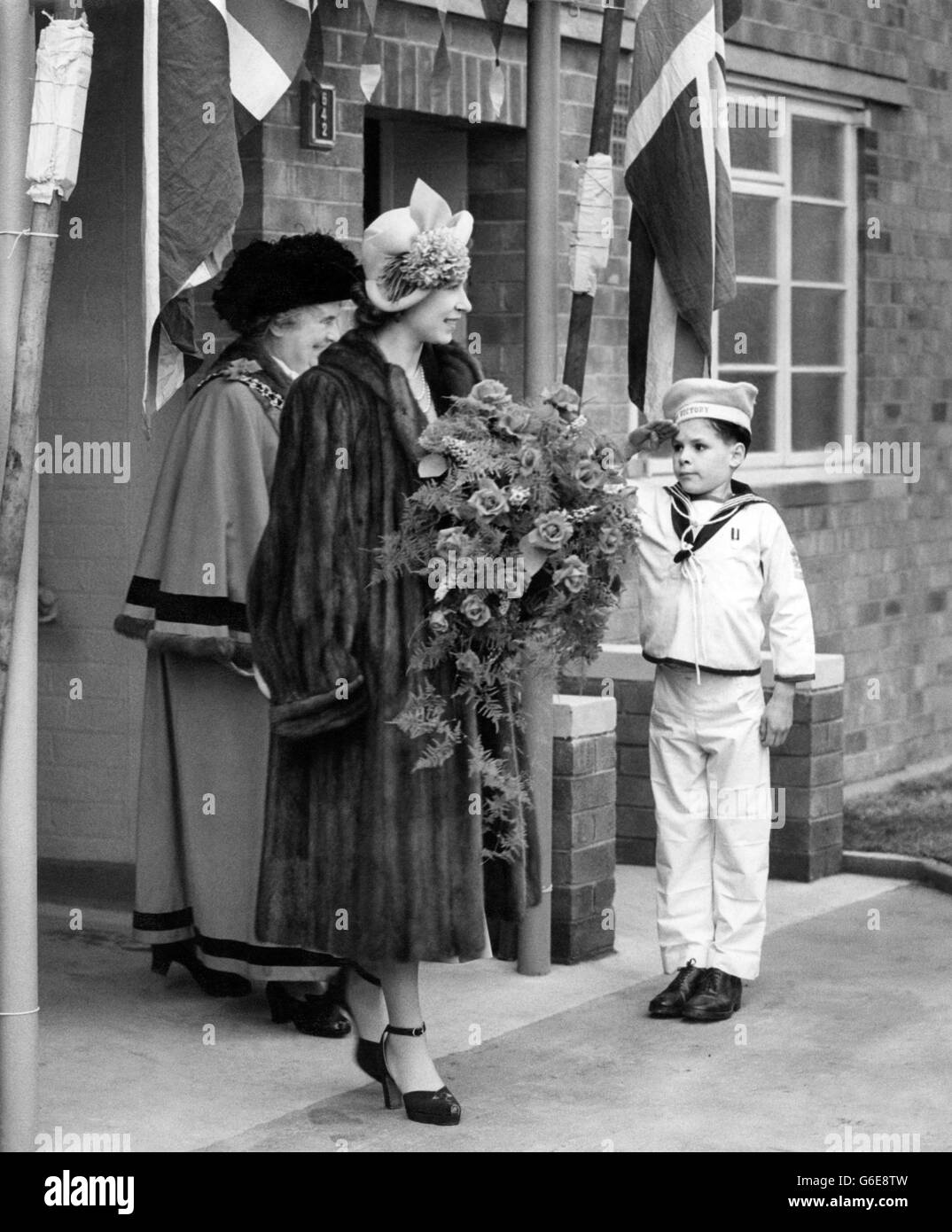 Un bambino in uniforme navale produce un saluto intelligente per LA PRINCIPESSA ELISABETTA quando arriva allo schema di riqualificazione della New Cross per vedere la 6.000 a casa post-bellica di Manchester, un appartamento occupato dal signor e dalla signora Stephen Egerton. Accompagnandola è la donna Signore Sindaco di Machester, Miss MARY KINGSHILL-JONES. Con il Duca di Edimburgo, la Principessa ha pagato la sua prima visita al Lancashire, il secondo giorno del tour di due giorni che è stato trascorso a Manchester. Foto Stock