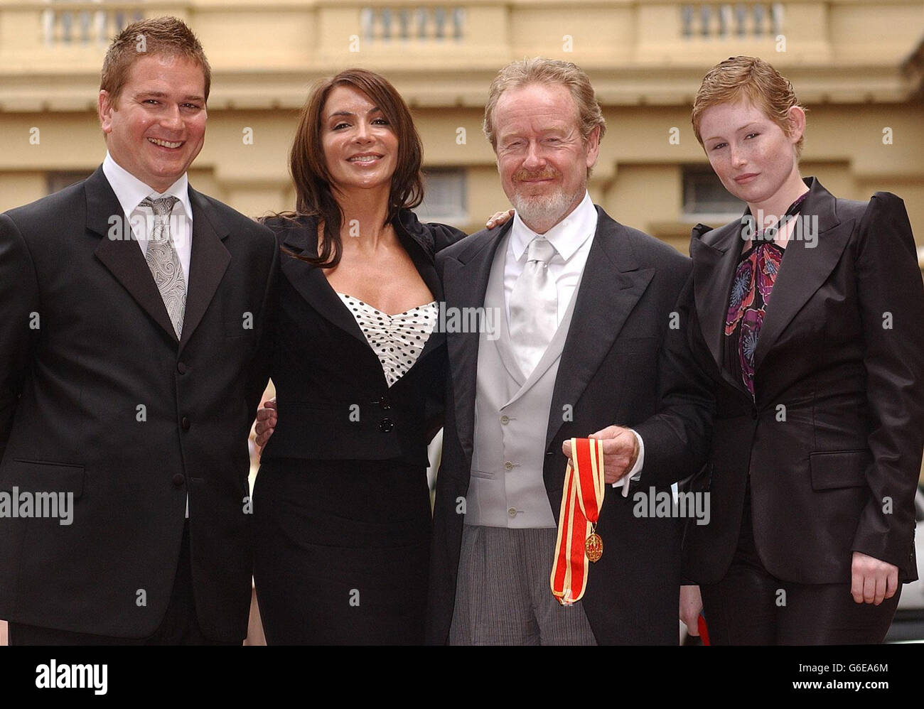 Sir Ridley Scott con il figlio Luke, la figlia Jordan (estrema destra) e la ragazza Giannina Fascio a Buckingham Palace, Londra, dopo che Sir Ridley fu nominato cavaliere dalla regina Elisabetta II Foto Stock