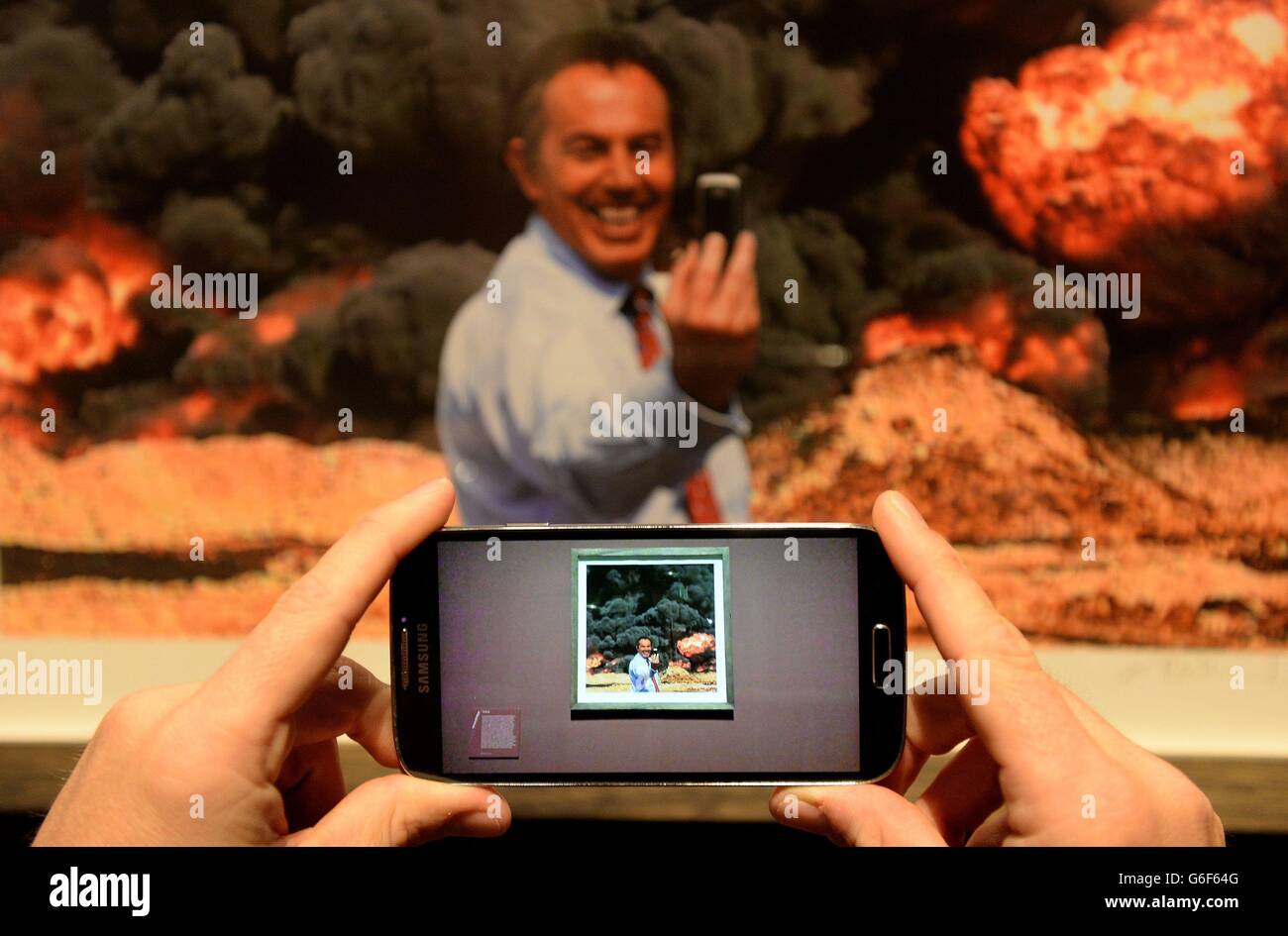 Un giornalista scatta una foto di Kennard Phillips 'Photo Op' un'immagine che raffigura l'ex primo ministro Tony Blair che ha preso un 'elfie' di fronte a un'esplosione in Iraq, durante una rassegna stampa della mostra Catalyst: Arte contemporanea e Guerra, che si svolge dal 12 ottobre 2013 al 23 febbraio 2014, presso l'IWM Nord. Foto Stock