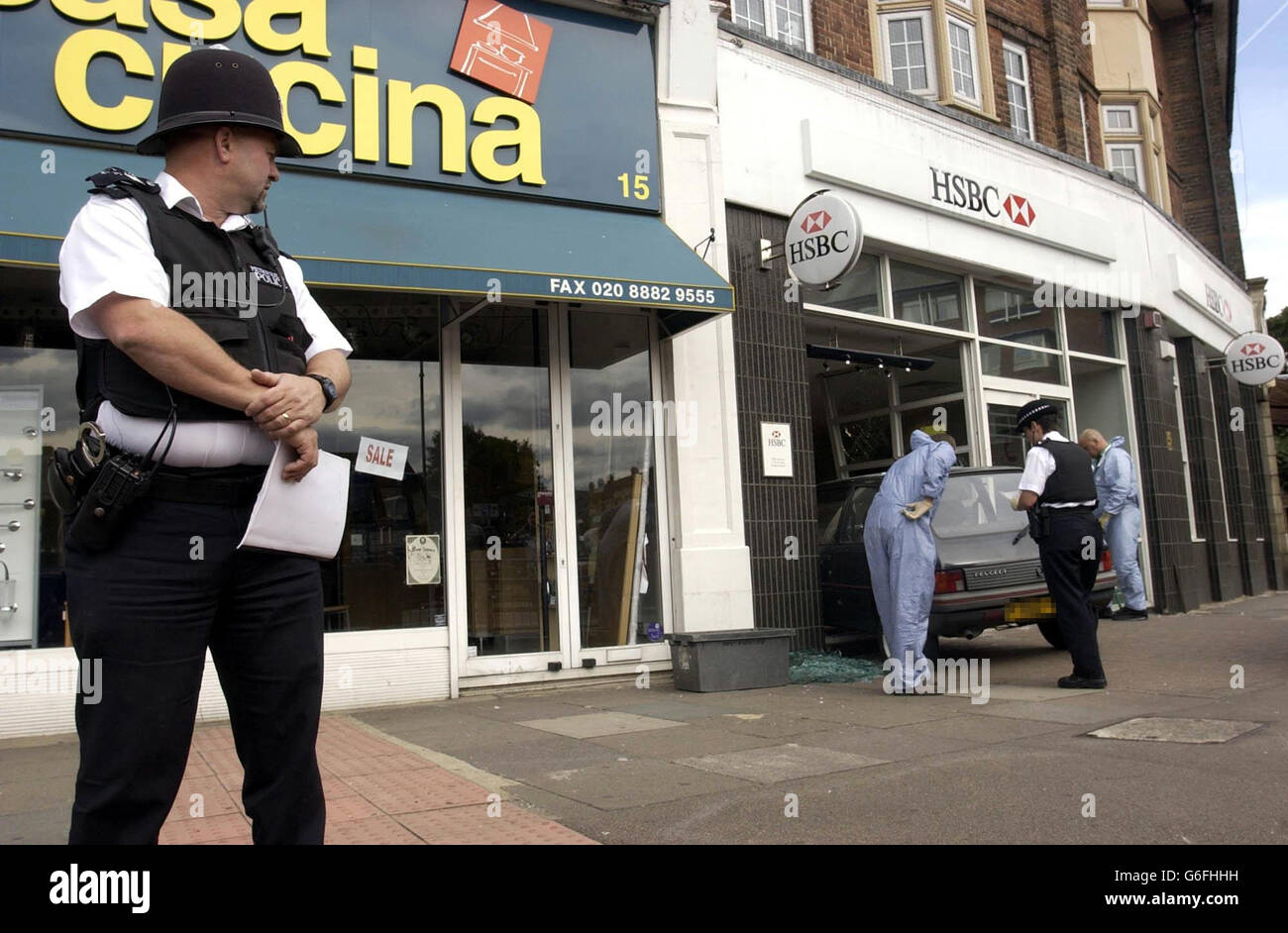 Polizia presso la banca HSBC a Southgate, nel nord di Londra, dopo una rapina armata che ha avuto luogo. Un uomo di sessant'anni è stato ferito durante il raid, mentre ha cercato di fermare i due ladri di allontanarsi dalla banca. * i ladri avevano fatto irruzione sulla banca usando la Peugeot 205, rubarono denaro dal distributore di contanti e fuggirono. Foto Stock