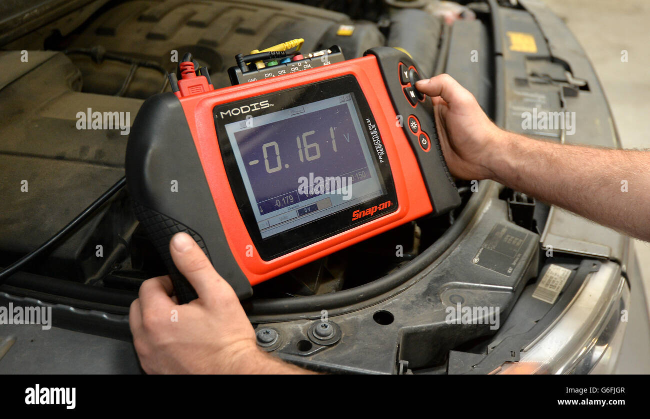 Scorte di riparazione auto. Un meccanico utilizza un sistema informativo diagnostico modulare MODIS a scatto sui componenti elettronici di un'auto Foto Stock