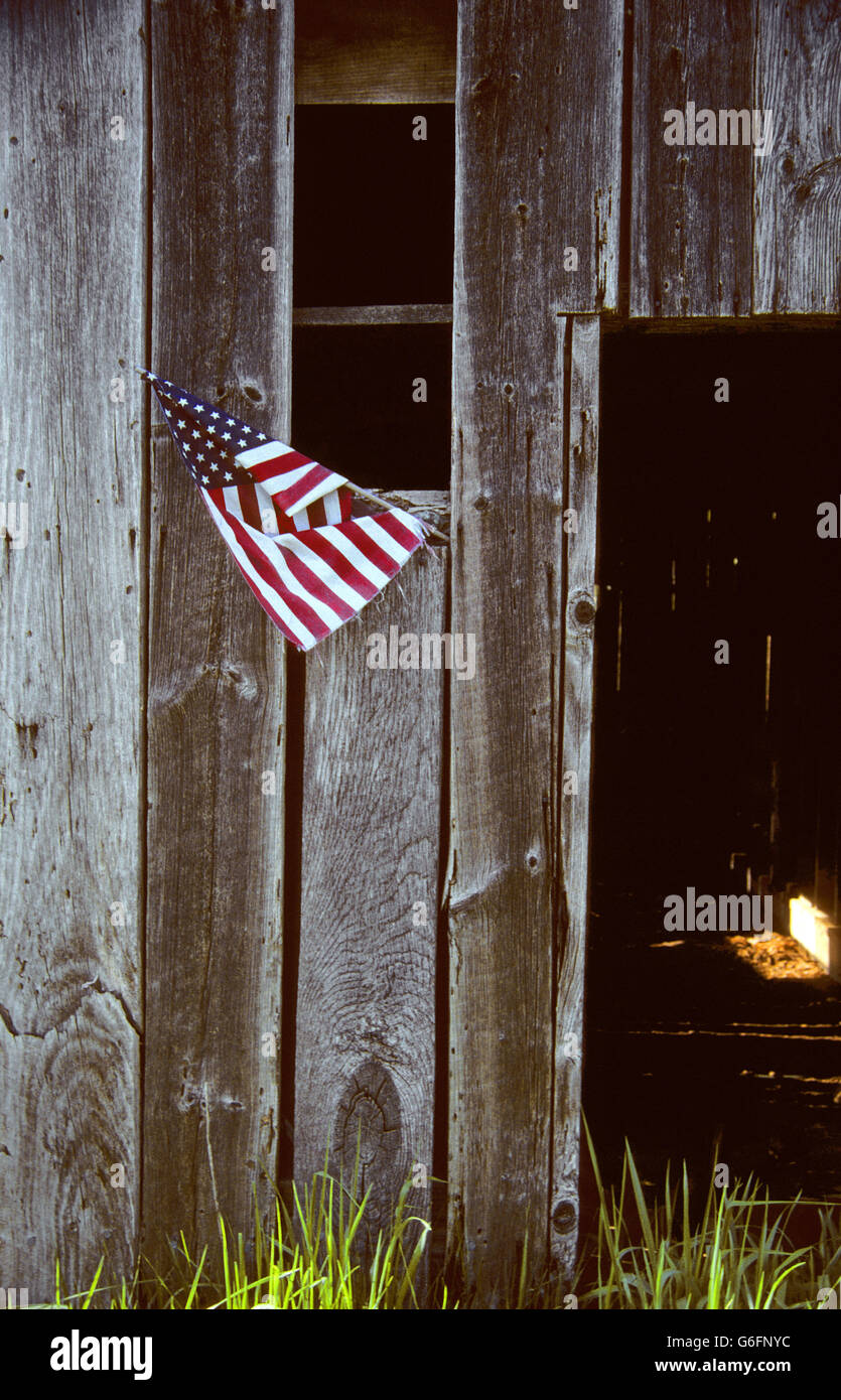 Un fienile stradale primitivo in Carolina del Nord, USA presenta una piccola bandiera americana appesa da una finestra che si apre. Foto Stock