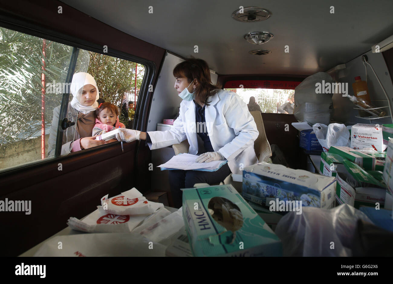 Un'infermiera fornisce medicinali ai rifugiati siriani da una clinica mobile della Caritas a Taalabaya, in Libano. Foto Stock