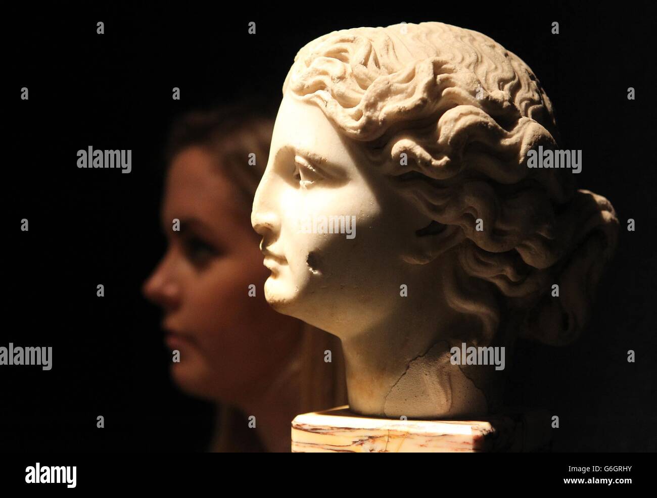 Un membro dello staff di Christie con una testa di marmo romano femmina con una stima di &sterlina;15.000-&sterlina;20.000 che fa parte di una collezione di antichità chiamate le origini dell'arte che saranno vendute nel mese di ottobre. Foto Stock