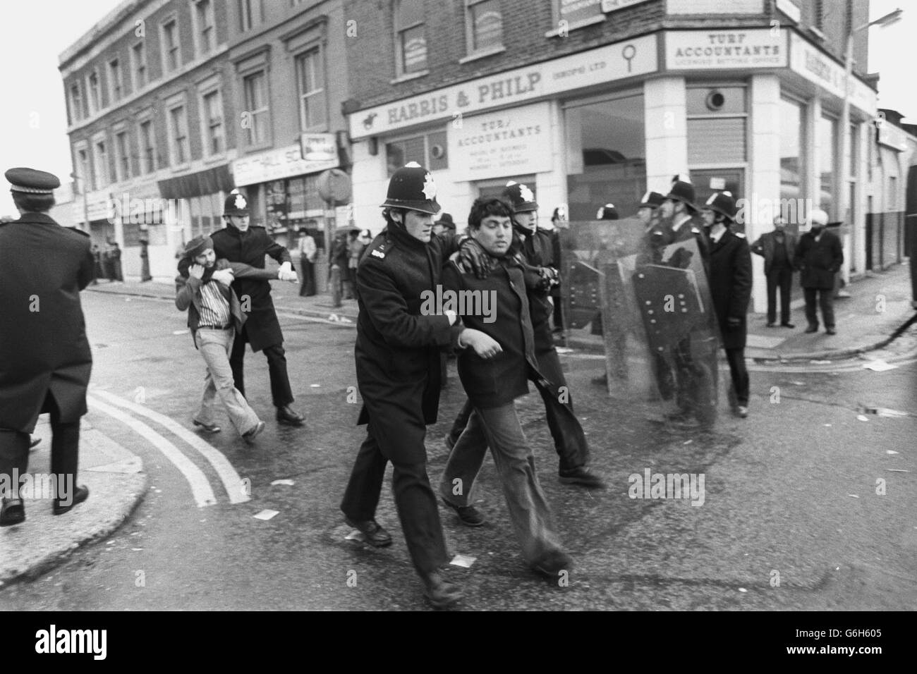 La polizia con scudi antisommossa sta accanto ai dimostranti che si accamparono ai furgoni in attesa a Southall dopo che una battaglia a colpi di falco ha scoppiato il municipio locale dove si stava svolgendo un raduno sul fronte nazionale. Numerosi poliziotti e manifestanti sono stati feriti durante i combattimenti. Foto Stock