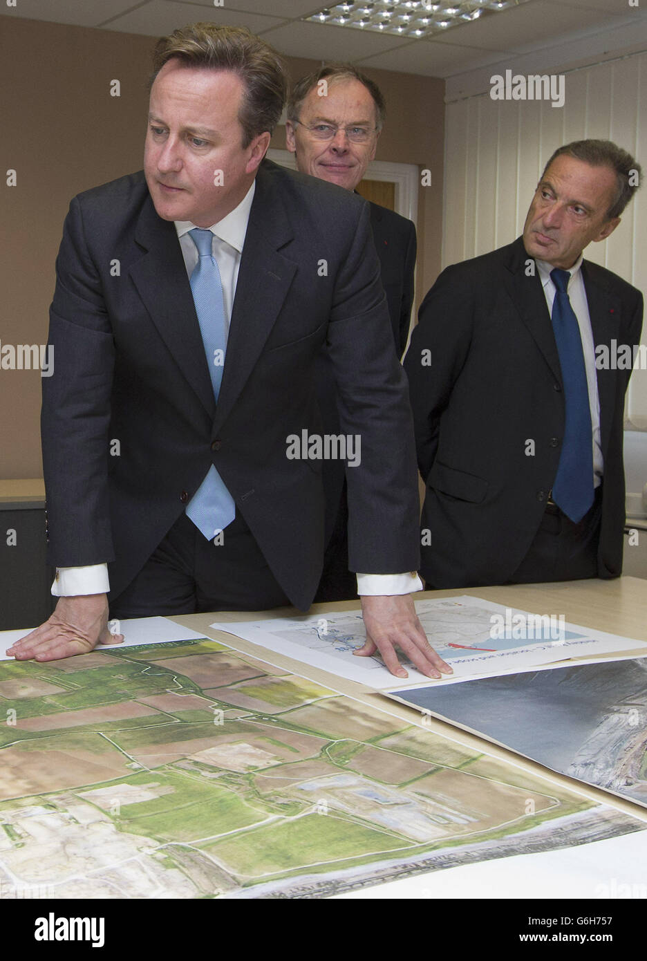 Il primo Ministro David Cameron con , Vincent de Rivaz, Chief Executive di EDF (Electricite de France) e Henri Proglio, CEO e Presidente di EDF (Right), mentre esaminano i piani del sito per la centrale nucleare di Hinkly C a Hinkley Point, Somerset. La prima nuova centrale nucleare britannica di una generazione sarà costruita nel quadro del progetto &Acirc;&Pound;16 miliardi che creerà migliaia di nuovi posti di lavoro. Foto Stock
