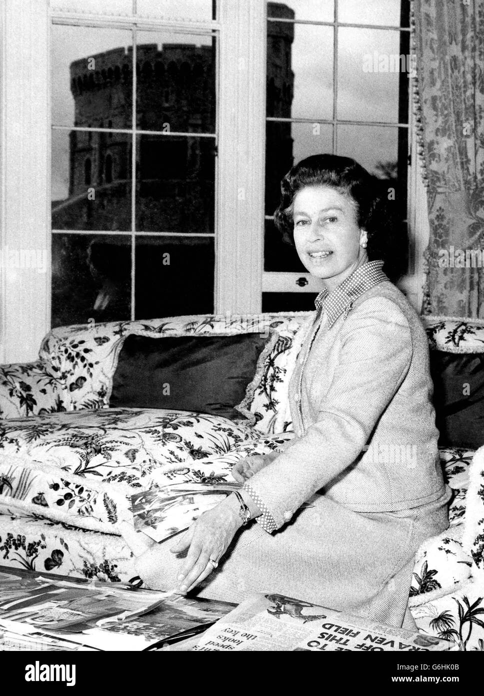 La regina nel suo salotto - una stanza con una vista della Torre rotonda - al Castello di Windsor mentre si prepara per il suo Silver Jubbliee tour della Gran Bretagna che inizia domani. Indossando un vestito e una giacca di trifoglio e lana bianca flecked, sta osservando le fotografie prese durante il giro della Jublee d'Argento del Pacifico del Sud e dell'Australasia. Foto Stock