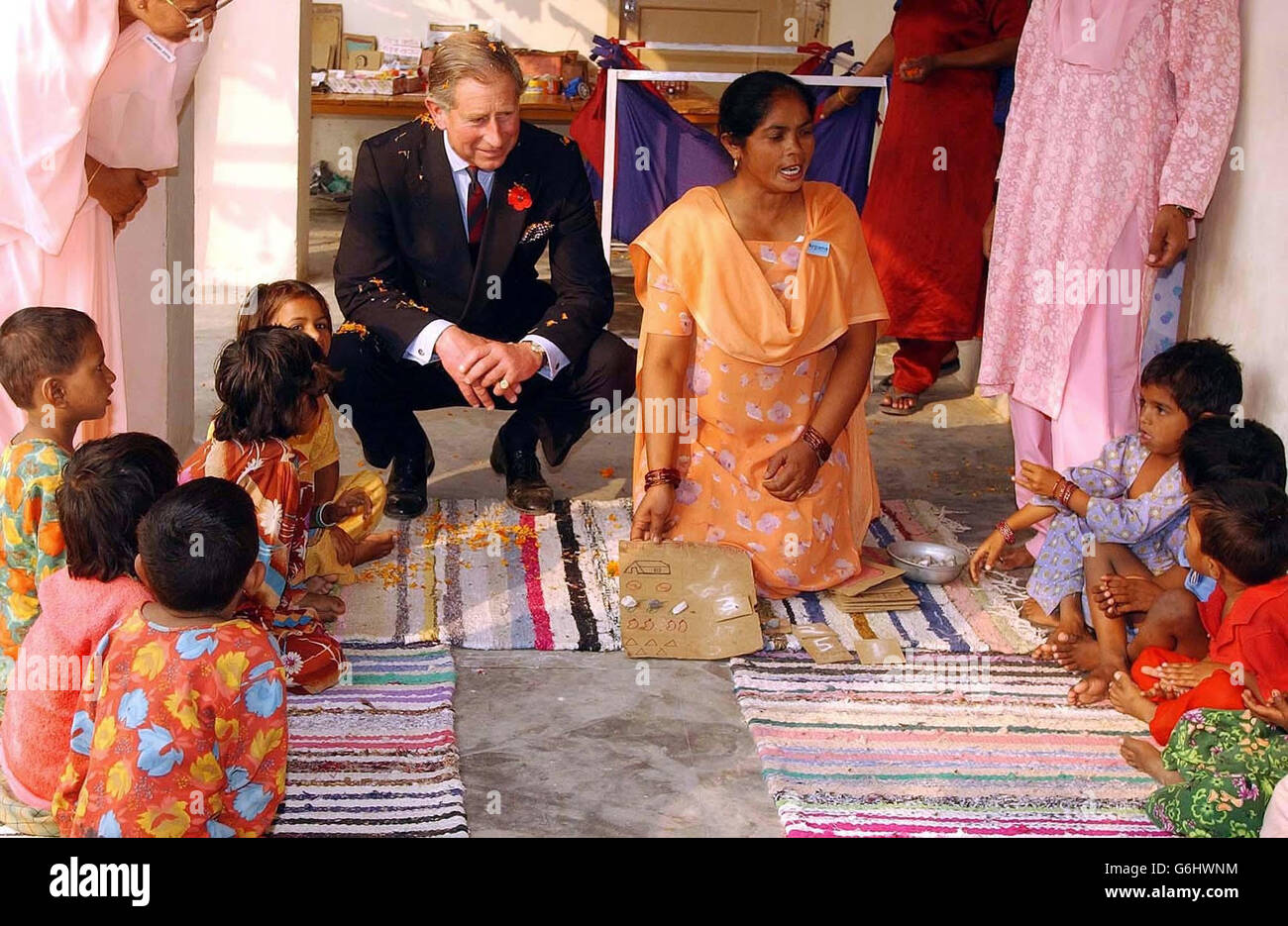 Il Principe del Galles si accoccolò per guardare i bambini giocare nella nursaria del villaggio di Kutail Gamri, alla periferia di Delhi, India, come parte della sua visita nella zona. Foto Stock